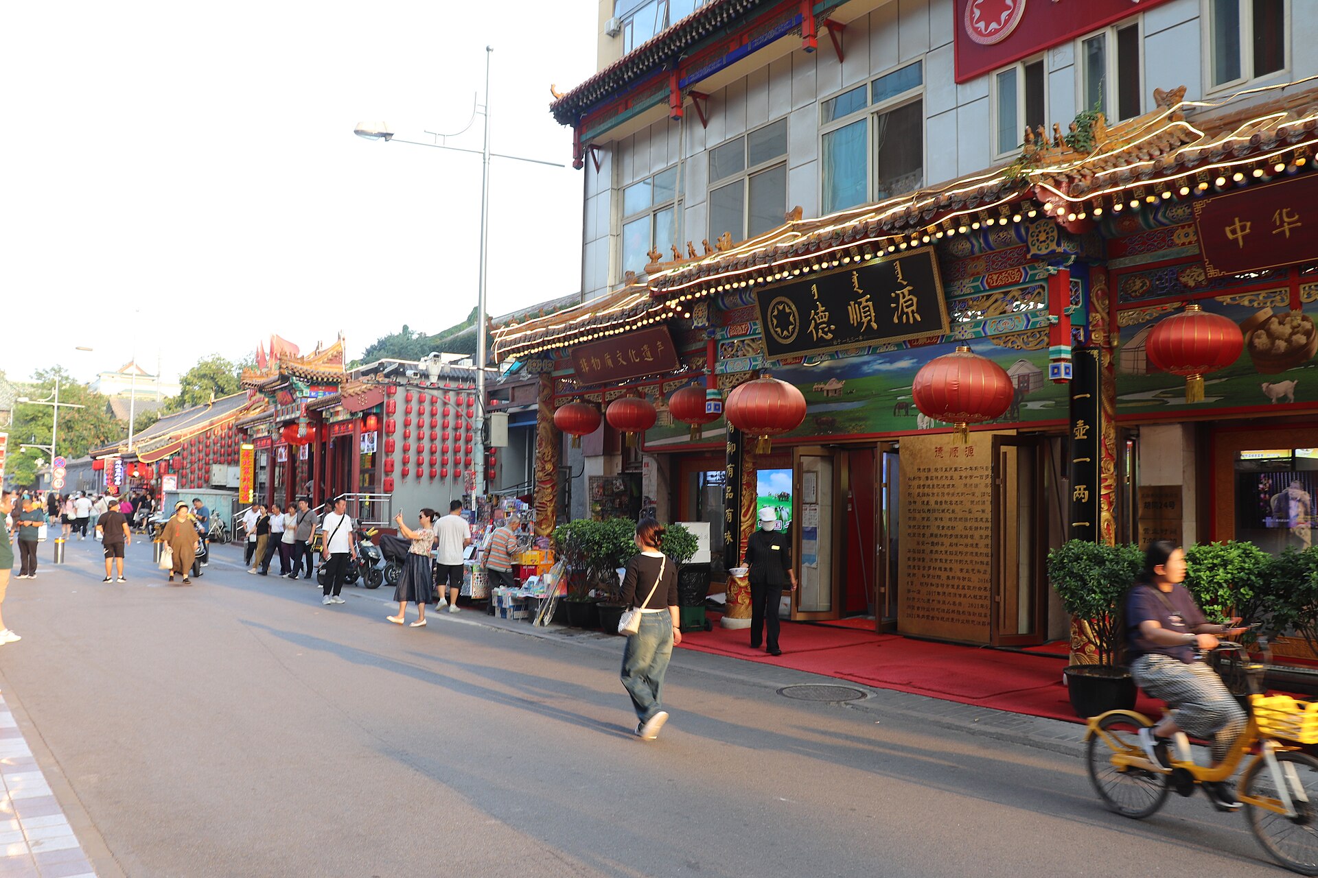 Pedestrians and a cyclist moving through Shuaifu Hutong in Beijing