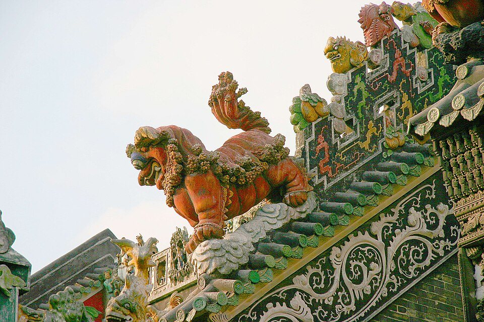 A ceramic guardian and ornamental forms rising along a roof ridge at Chen Clan Ancestral Hall