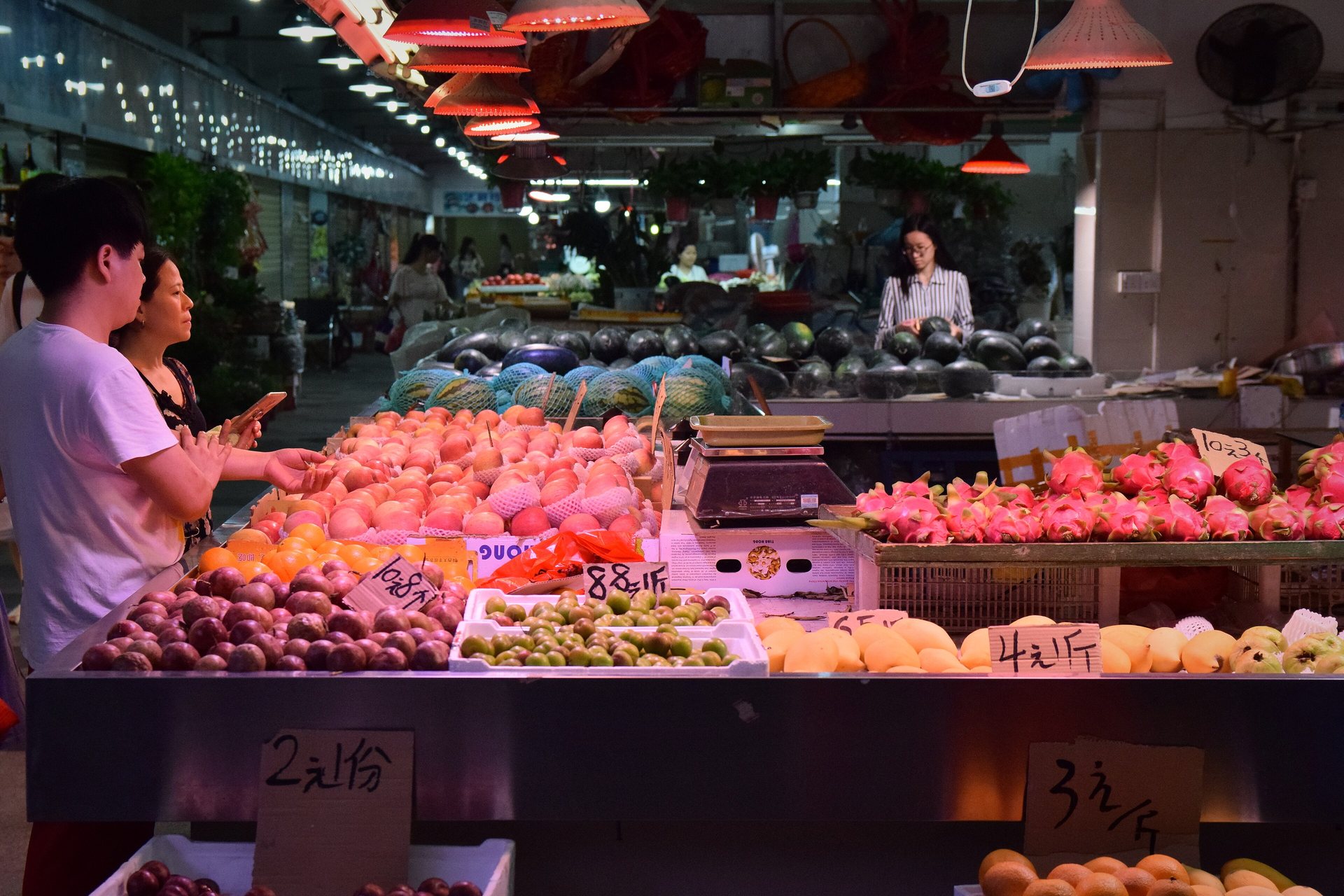A fruit stall with a vendor and customer in a Guangzhou market
