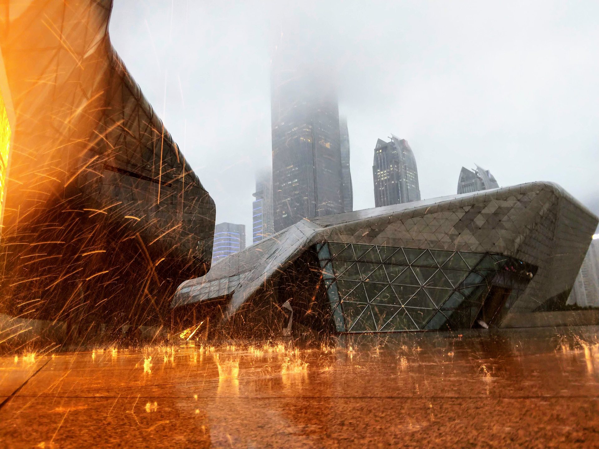 Rainwater splashes lit near Guangzhou Opera House with Zhujiang New Town beyond
