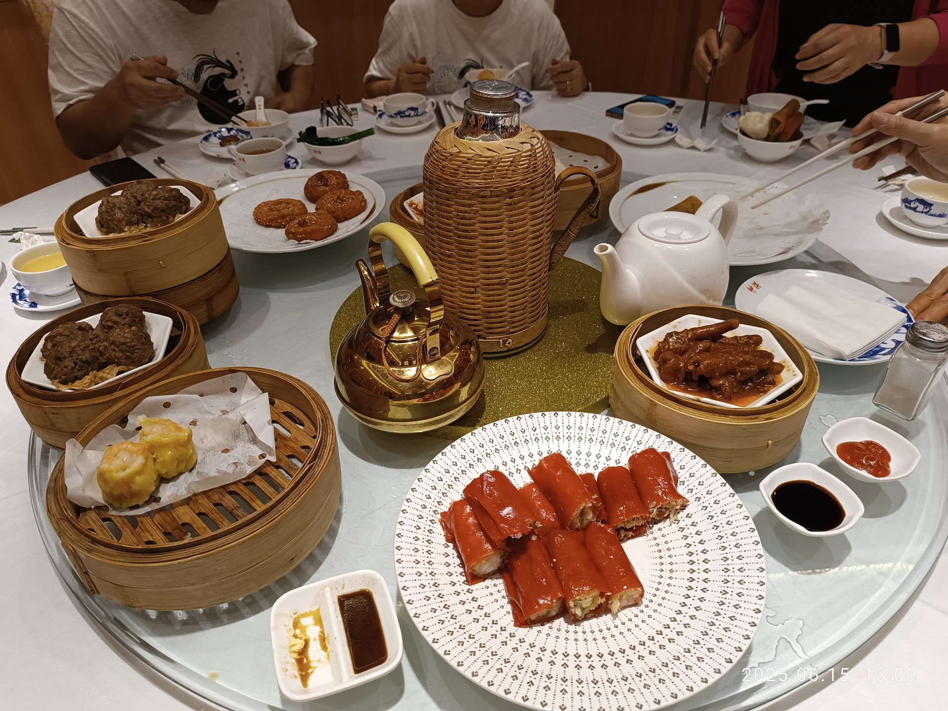 Tea, dim sum, and several diners' hands around a shared restaurant table in Guangzhou