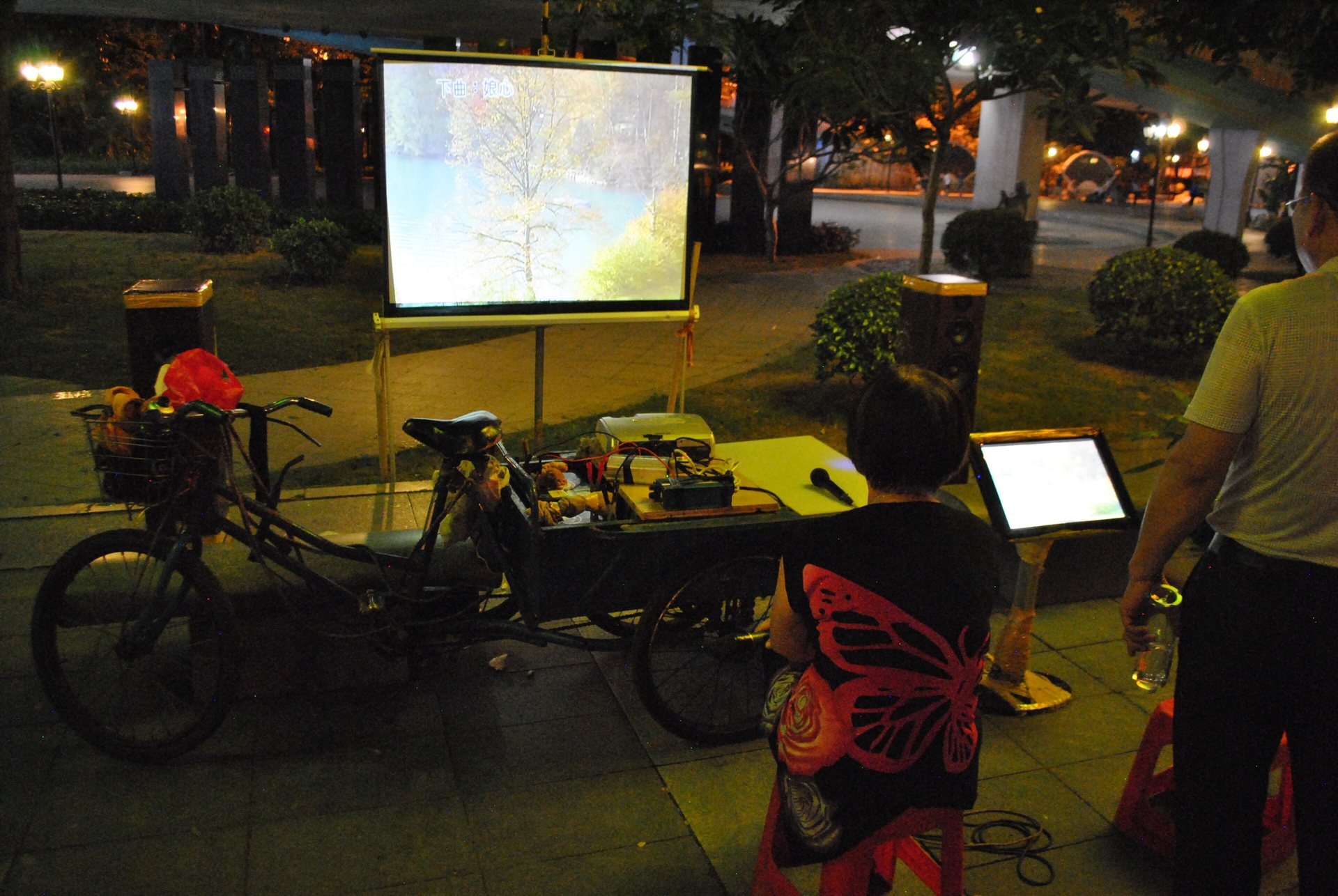 People gathered around a mobile karaoke setup on the Pearl River promenade