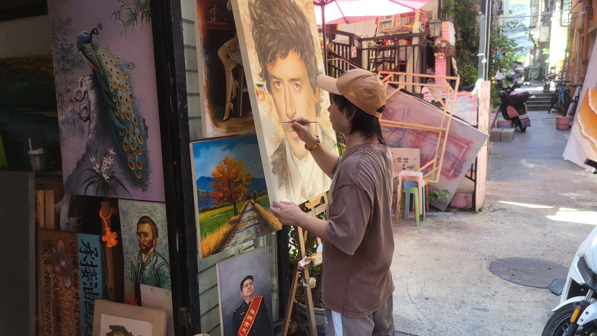 A painter working on a portrait among sample paintings in Dafen